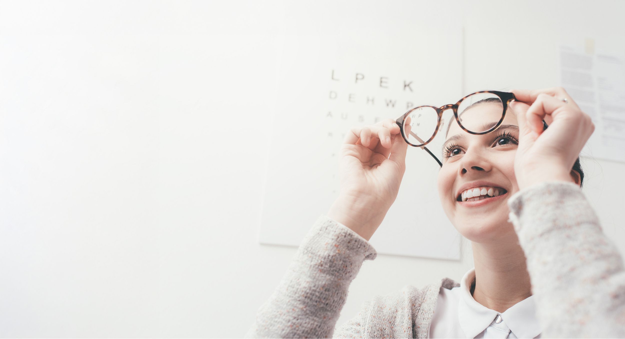 Lächelndes Mädchen probiert beim Optiker eine Brille